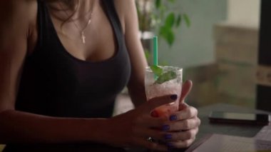 Çekici genç bir kadın buz dolu bir kokteyl tutarak atış kapatın.