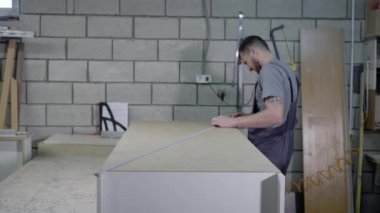 Bir atölyede büyük bir kitaplık ölçümleri alarak erkek işçi.