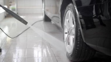 Yakın çekim yüksek basınçlı su jeti bir carwash araba yıkamayı kullanan bir adam ups.
