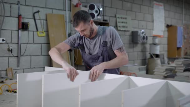 Tischler, der in einer Werkstatt sorgfältig Teile eines Regals zusammenfügt. — Stockvideo