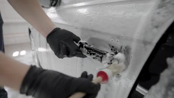 Gros plan d'un homme utilisant une brosse pour nettoyer les poignées de voiture . — Video