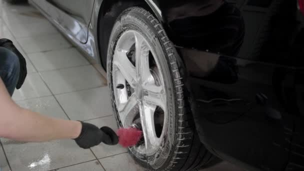 Close-up shot van een man het wassen van auto schijven in carwash. — Stockvideo