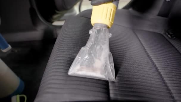 Close up shot of a man vacuuming the seat of a car in carwash. — Stock Video