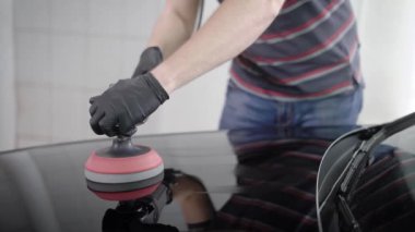 Parlak siyah araba kukuIeta carwash istasyonunda fotoğrafını kapatın. Dikkatle parlatma makinesi ile büyük bir meme kullanarak parlatma dostum.