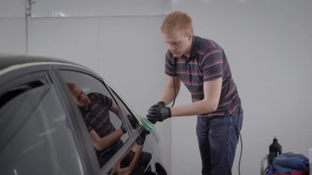 Επαγγελματική εργαζόμενος του σταθμού carwash προσεκτικά στίλβωση καθαρή αυτοκινήτων με μια μηχανή γυαλίσματος. — Αρχείο Βίντεο