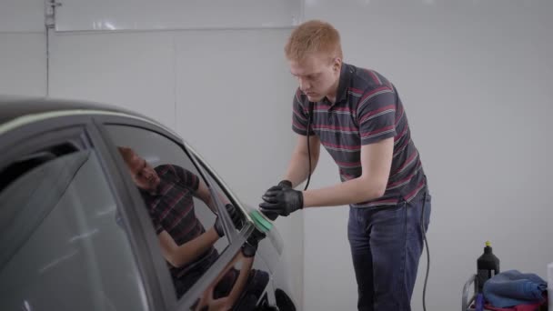 Professionele werknemer van carwash station zorgvuldig schone auto polijsten met een polijst machine. — Stockvideo