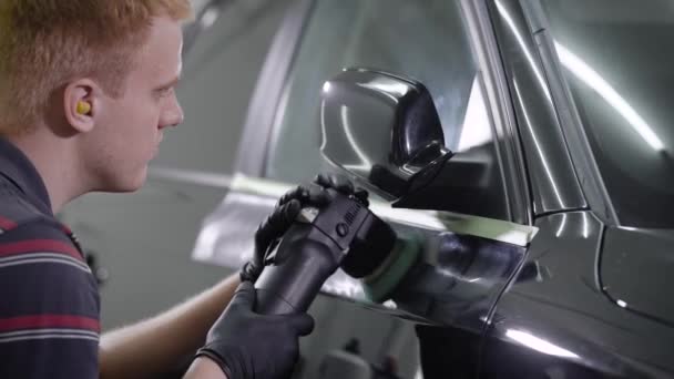 Close up tiro de um trabalhador de lavagem de carros encerando um carro preto com ferramenta especial . — Vídeo de Stock