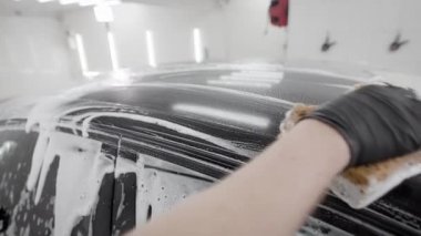 washerman siyah otomobil yüzeyi tarafından sünger sabun köpüğü ile araba yıkama, lastik eldiven, el yakın çekim sürtünme