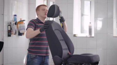 Oto yıkama çalışan elektrikli süpürge kullanma bir odada otomobil koltuk Temizleme, koltuk rafta duruyor