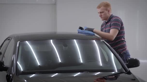 Man is cleaning automobile by cloth in a car washing room, rubbing roof, taking out dirt from surface — Stock Video