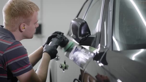Работник создает защитное покрытие на автомобильном красителе, протирая вращающимся шлифовальным станком в автосервисе — стоковое видео