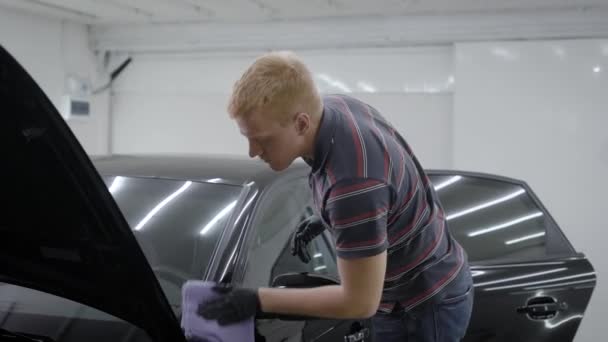 Mesin cuci adalah menyeka mobil hitam bersih dengan kain lembut setelah mencuci, memoles di sebuah ruangan lokakarya mobil — Stok Video