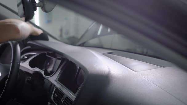 Washerman is wiping control panel of modern auto by black sponge, sitting inside, close-up of hand — Stock Video