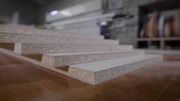 Trozos cortados de aglomerado se encuentran en una mesa de trabajo en un taller de carpintería, primer plano de tiro móvil en la planta de muebles — Vídeos de Stock