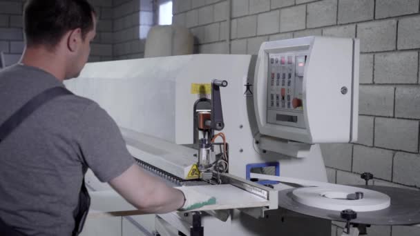 Майстер використовує промислову машину для обробки країв ДСП в майстерні меблевого заводу — стокове відео