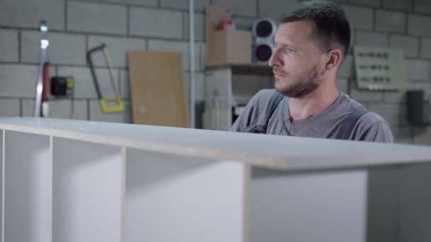 Мастер устанавливает вилки на деревянный гардероб после сборки в цехе мебельной фабрики, крупным планом — стоковое видео