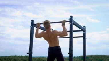 genç kaslı sporcu kol demiri açık havada yaz günde holding, sırt ve el kaslarının gerilmesini onun vücut kaldırma