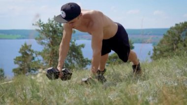 Erkek atlet zemin açık havada ve sabit dambıl, güneşli yaz günde eğitim onun cesedi bastırıyor