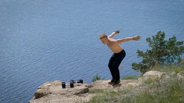 Ung extremvärden man utför kullerbytta i luften står på kanten av klippa i solig sommardag — Stockvideo