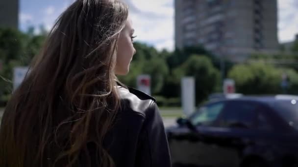 Een jonge vrouw benadert haar auto, welke tribunes op de parkeerplaats, de Dame de deur opent naar daar zitten — Stockvideo