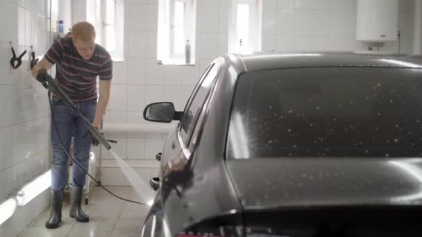 Man washing auto in car wash tiled room — Stock Video