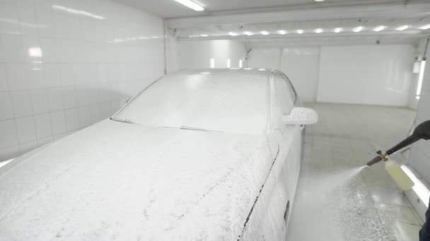 Hombre rociando con coche de espuma en habitación de baldosas blancas — Vídeos de Stock