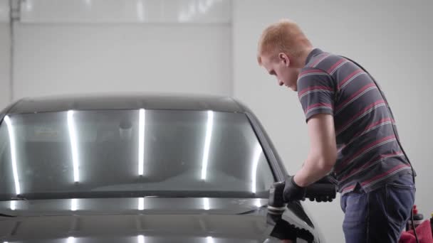 Vista lateral del hombre pulido coche con cera en el garaje — Vídeo de stock