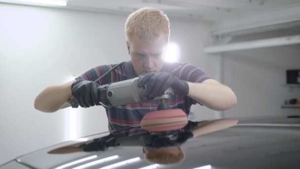 Man using polishing device while taking care of car in garage — Stock Video