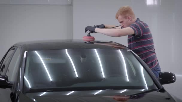 Vista lateral del hombre adulto de pie en el garaje y el uso de la máquina de pulido en el techo del coche — Vídeo de stock