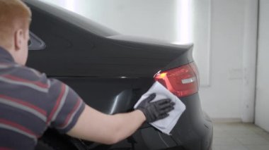 Siyah araba garajında arkasında silmek için havlu kullanarak adam arkadan görünüm 
