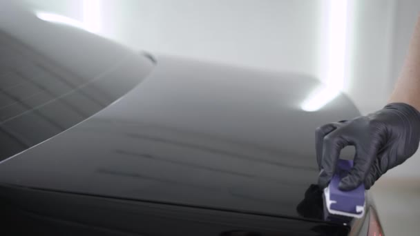 Erntehelfer setzen Poliermittel auf schwarzen Kofferraum in Garage — Stockvideo