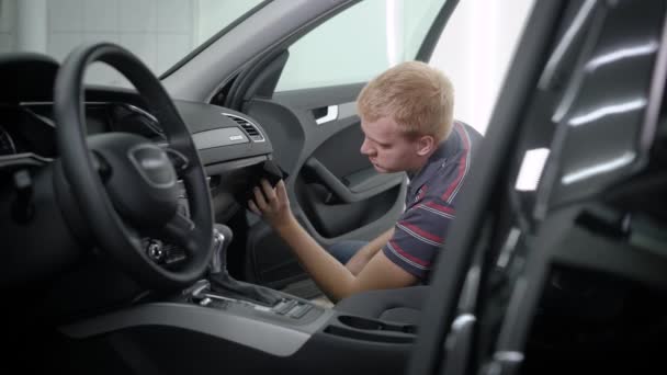 Sidovy av mannen sitter och tar hand om bilens interiör i garage — Stockvideo