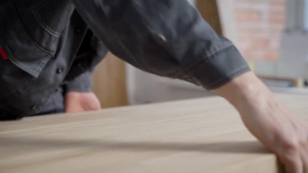 Человек в форме трогает руками свежую деревянную панель — стоковое видео