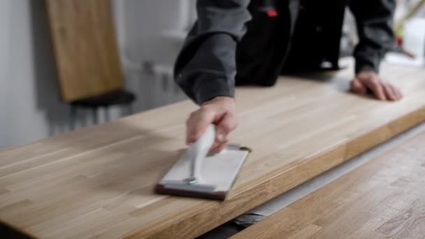 Hombre de pie y pulido escritorio de madera hecho a sí mismo con herramienta especial — Vídeo de stock