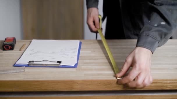 Lavoratore del legno che prende appunti su carta su tavola di legno con la lista dei nastri di misura — Video Stock