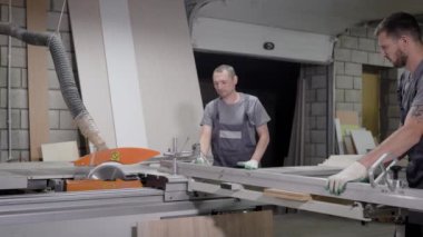 Ağaç kesme makinesi duran üniformalı fabrikasında çalışan erkekler