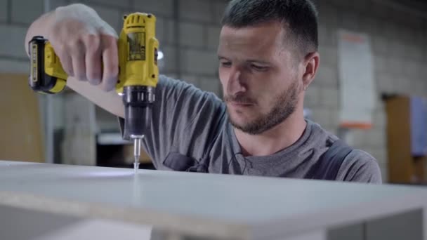 Hombre trabajador usando taladro para panel de madera en blanco de fábrica — Vídeos de Stock