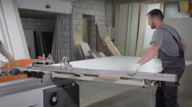 Endüstriyel marangoz işçilerin ahşap kesme makinesi üzerinde çalışma.