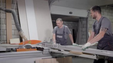 Sanayi işçileri bir kesme makine üzerinde çalışan.