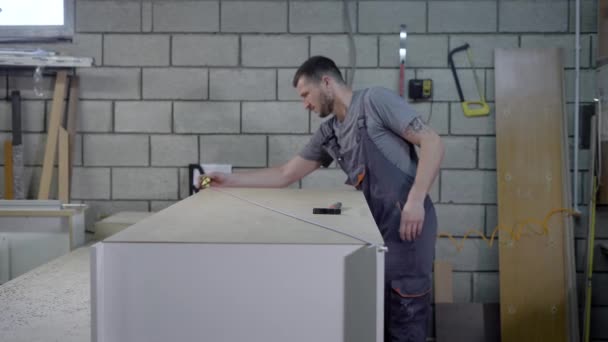 Carpinteiro cuidadosamente adquirindo partes de uma prateleira em conjunto em uma oficina . — Vídeo de Stock