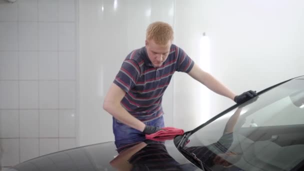 赤毛男性ワーカーが処理車のサービスで研磨機によって車の表面保護層をカバー — ストック動画