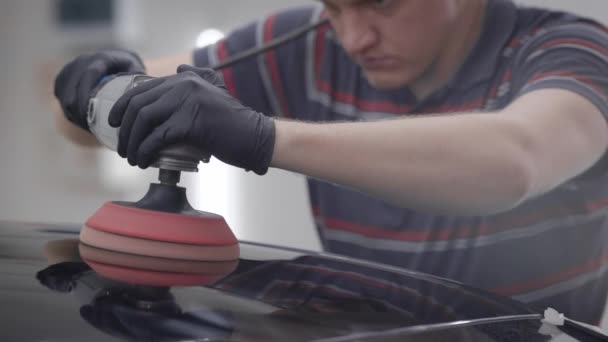 Maître broie un toit d'automobile noire propre lors de la fabrication d'un revêtement de protection dans un garage — Video