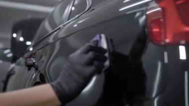 Siyah araba garajında arkasında silmek için havlu kullanarak adam arkadan görünüm