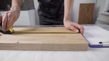 İşçi el çerçevede. Birleştiriciyi boyutu ahşap tahta üzerinde işaretler. Bir mezura ve bir kalem kullanır
