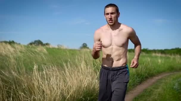 Portret van een gespierde shirtless man die dwars over het veld. — Stockvideo