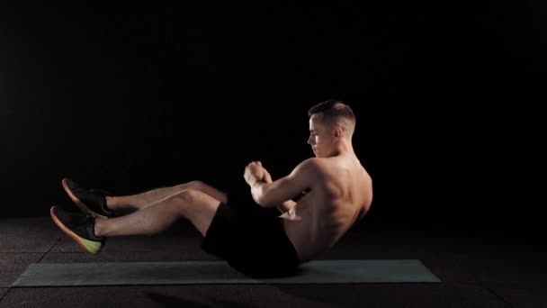 Profisportler macht russische Drehungen auf einer Matte in einem Fitnessstudio. — Stockvideo