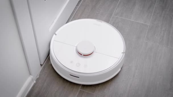 Στο πλαίσιο είναι ένα ρομπότ ηλεκτρική σκούπα που καθαρίζει το πάτωμα στην κουζίνα. — Αρχείο Βίντεο