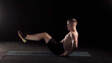 Güçlü delikanlı bir fitness merkezinde spor mat, yükselen bacak ve gövde yerden yatan eğitiyor