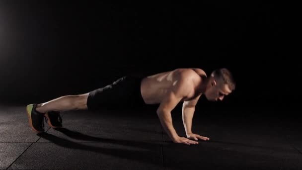 Мужчина делает отжимания с пола с прыжками в тренажерном зале, он тренируется один, готовится к соревнованиям — стоковое видео
