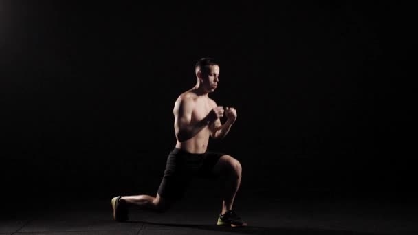 Culturista está realizando saltos con embestidas en una sala de fitness oscura, entrenar los músculos de sus piernas y resistencia — Vídeos de Stock